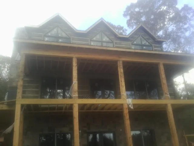 Dormers and porch framing on a large log home under construction — Roof Coating work by our crew in Saltillo