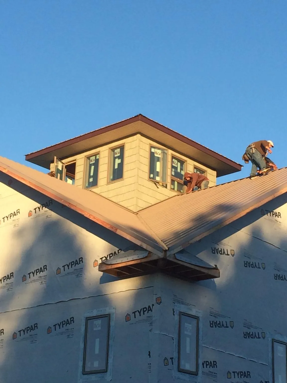 Roofers working around a rooftop cupola on a new metal roof at sunset — Roof Waterproofing in Saltillo by Roofing Brothers